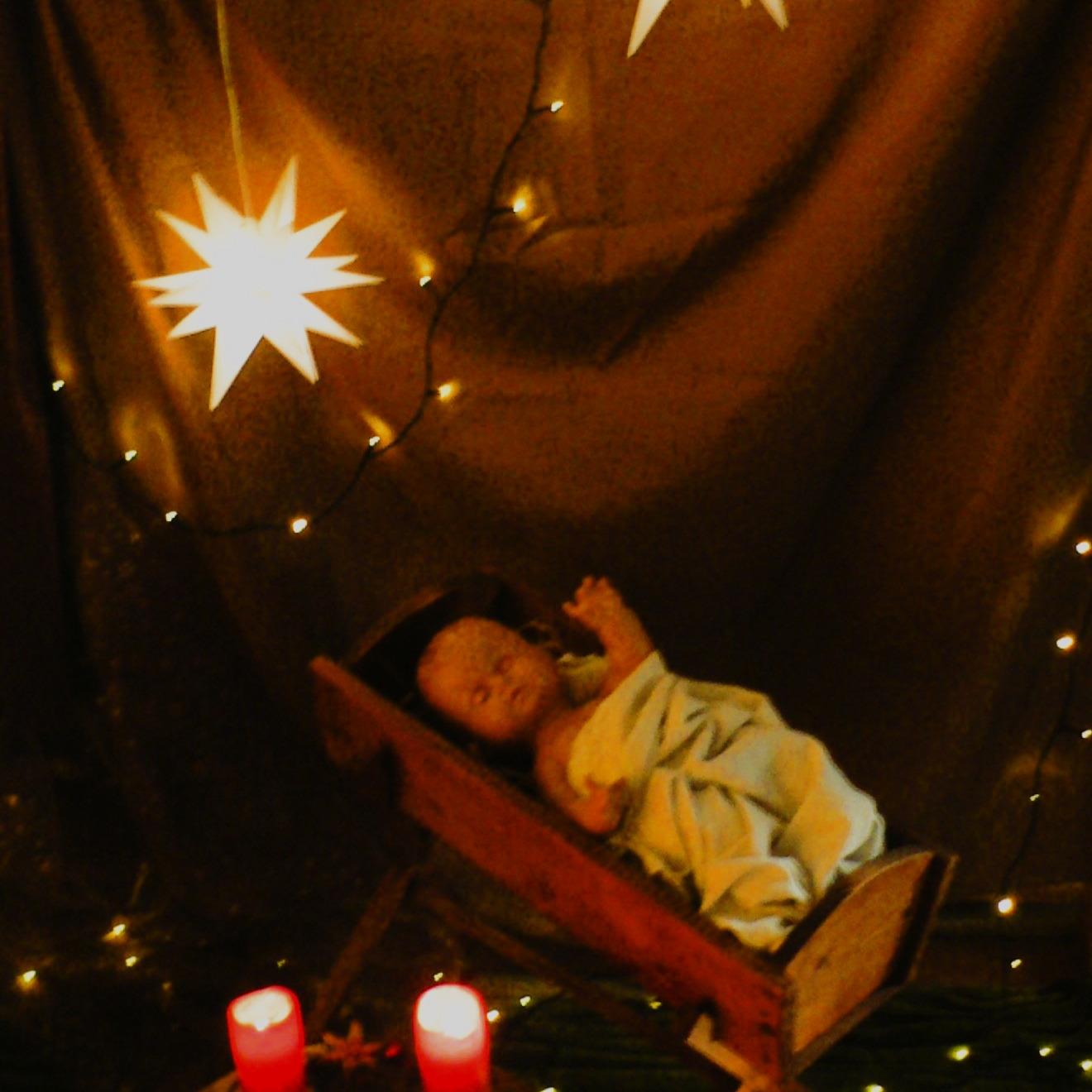 Christuskind in Krippe mit Adventskranz