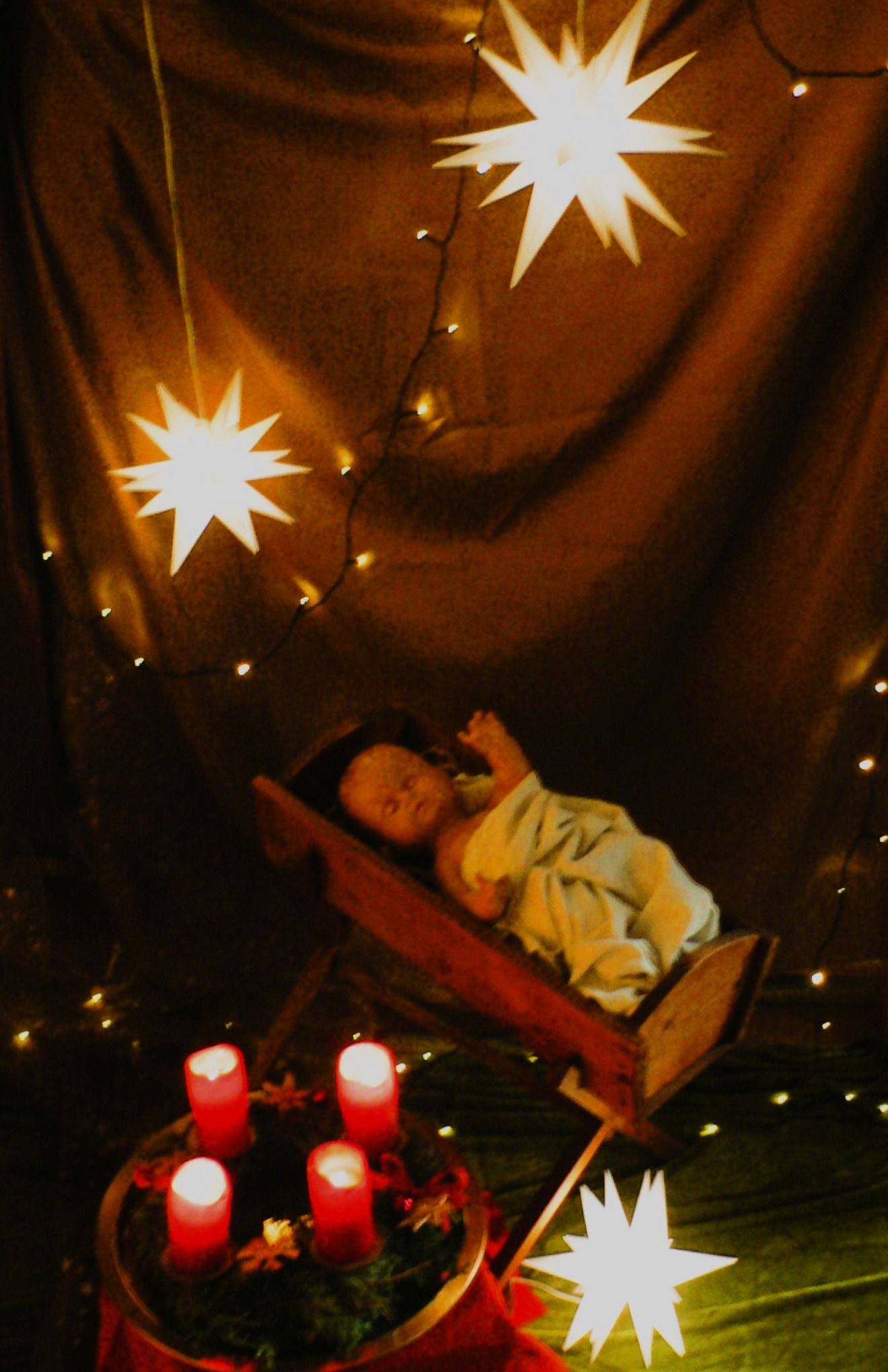 Christuskind in Krippe mit Adventskranz